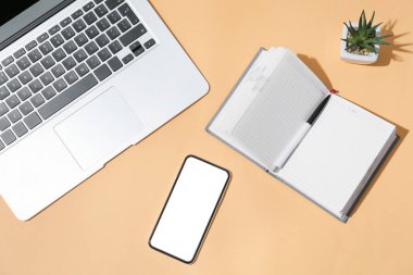 Renkli arka planda cep telefonu, defter, kalem ve dizüstü bilgisayar