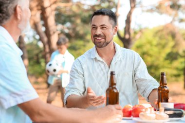 Handsome man with bottle of beer at barbecue party on summer day