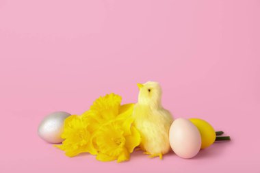 Sevimli sarı tavuk, Paskalya yumurtası ve pembe arka planda çiçekler.