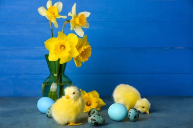 Tatlı tavuklar, Paskalya yumurtaları ve çiçekler masada.