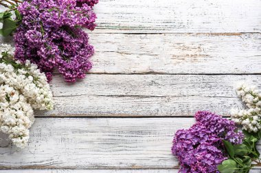 Beyaz ahşap zemin üzerinde leylak çiçeklerinden yapılmış çerçeve