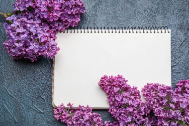 Koyu arkaplanda defter olan mor leylak çiçekleri.