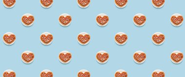 Açık mavi arka planda bir sürü kalp şeklinde pizza. Tasarım için desen