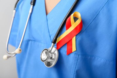 Gri arka planda farkındalık kurdelesi ve steteskobu olan kadın doktor, yakın plan. Hepatit konsepti