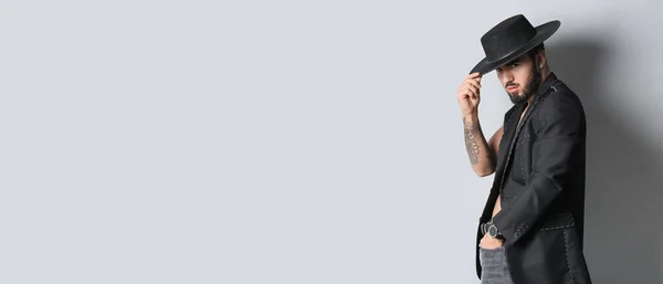 Fashionable bearded tattooed man on light background with space for text