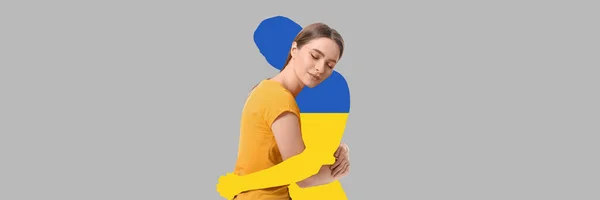 年轻女子抱着灰色背景的乌克兰国旗的轮廓 — 图库照片