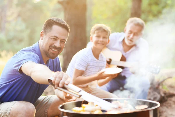 在烧烤派对上 英俊男子与家人一起在烤架上做饭 — 图库照片