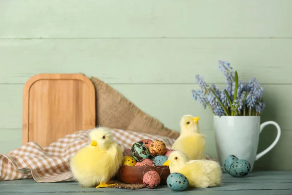 Cute chickens, Easter eggs and flowers on table