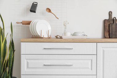 Interior of light kitchen with white drawers and utensils