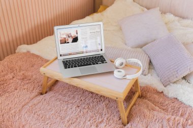 Yatak odasında açık gazete ve kulaklıklı dizüstü bilgisayar.