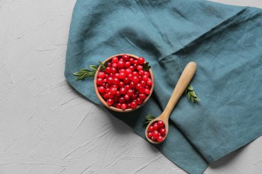 Kase, yaban mersinli kaşık ve gri arka planda peçete.