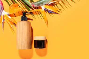 Cosmetic products and strelitzia flowers on color background
