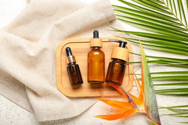 Ahşap tahta tahta tahta, kozmetik ürünler şişeleri, strelitzia çiçeği ve açık arkaplanda palmiye yaprağı