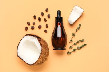 Hindistan cevizi, kahve çekirdeği ve bej arkaplanda kekik bulunan bir şişe doğal serum.