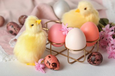 Tatlı tavuklar, Paskalya yumurtaları ve çiçekler ışık masasında.