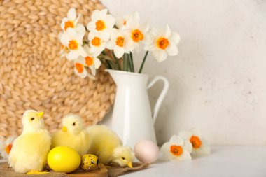 Tatlı tavuklar, Paskalya yumurtaları ve çiçekler ışık masasında.