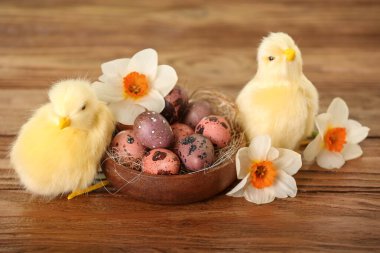 Şirin tavuklar, Paskalya yumurtaları ve tahta masanın üzerindeki çiçekler.
