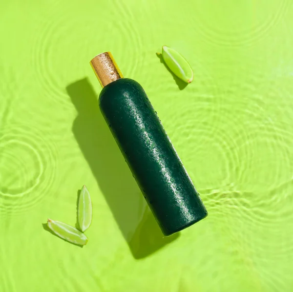 绿色背景的洗发水瓶和水里的石灰 — 图库照片