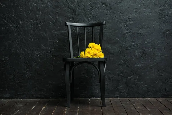 Fekete Szék Sárga Virágokkal Sötét Fal Közelében — Stock Fotó