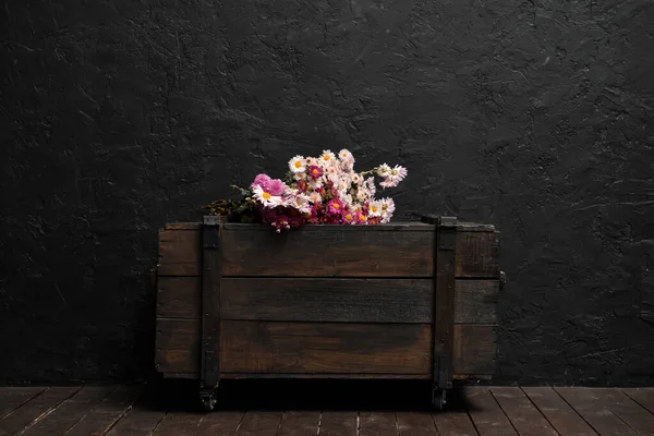 深色墙边抽屉木箱上的美丽花朵 — 图库照片
