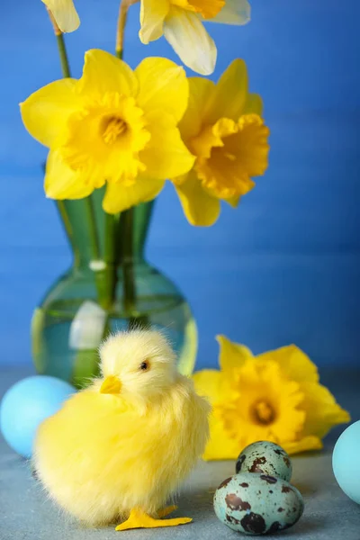 Cute chicken, Easter eggs and flowers on table