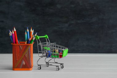 Alışveriş arabası ve elinde kırtasiye malzemesi var.