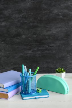 Different stationery on table near black wall