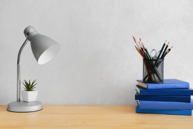 Modern lamba ve farklı kırtasiye malzemeleri ışık duvarının yanındaki masada.
