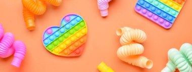 Pop tüpleri ve popo turuncu arka planda oyuncakları kıpırdatır. Tasarım için pankart