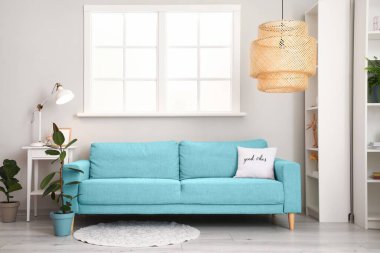 Pencerenin yanındaki mavi kanepeli modern oturma odasının içinde.