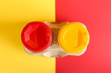 Holder with takeaway paper cups on color background