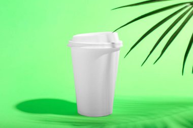 Yeşil arka planda paket kâğıt bardak ve palmiye yaprağı