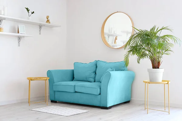 Interior of light living room with blue sofa and houseplant