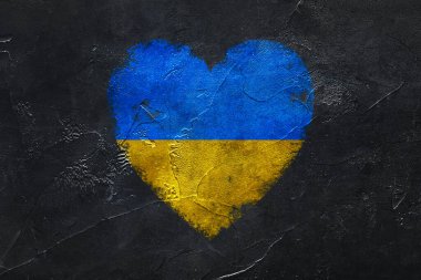Painted heart in colors of Ukrainian flag on dark grunge background