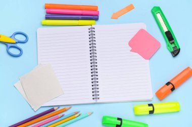 Mavi arkaplanda kırtasiye malzemesi olan boş bir defter