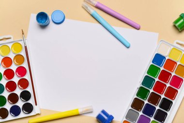 Bej arka planda boya ve keçeli kalemlerle dolu boş kağıt kağıtlar.