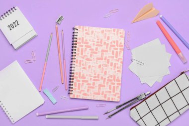 Different stationery supplies with calendar on lilac background
