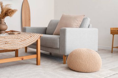 Rahat bir kanepe, puf ve masa oturma odasındaki ışık duvarının yanında.