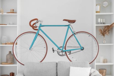 Aydınlık oturma odasındaki gri koltukta modern bisiklet.