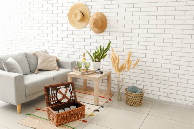 Oturma odasındaki halıda piknik için sofra takımı olan sepet.