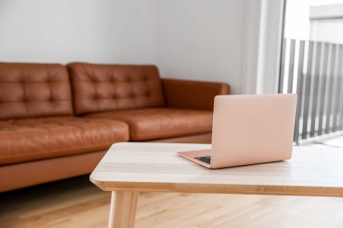 Laptop, oturma odasındaki ahşap sehpanın üstünde.