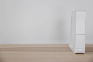 Işık duvarının yanındaki masada modern beyaz kablosuz ağ yönlendirici