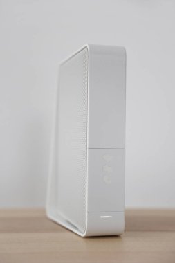 Işık duvarının yanındaki masada modern beyaz kablosuz ağ yönlendirici