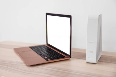 Modern laptop ve wi-fi yönlendirici beyaz duvarın yanındaki masada.