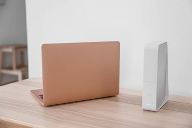 Modern laptop ve wi-fi yönlendirici ışık duvarının yanındaki masada.