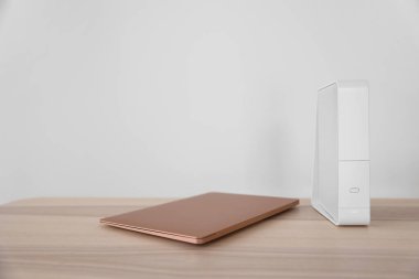 Modern laptop ve wi-fi yönlendirici ışık duvarının yanındaki masada.