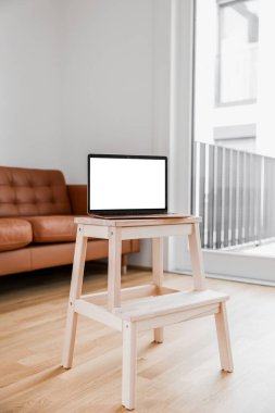 Modern laptop on step stool in living room