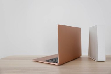 Modern laptop ve wi-fi yönlendirici ışık duvarının yanındaki masada.