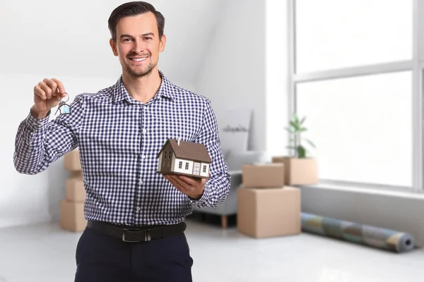 Male real estate agent with figure of house and key indoors
