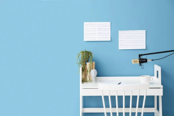 Modern workplace of composer and stand with professional microphone near color wall in room interior